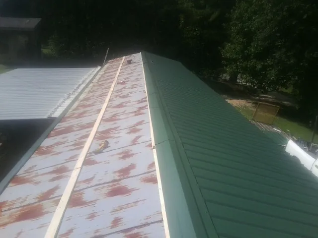 Old rusted panels beside newly installed green metal roofing — Wind Damage Roof Repair by Roofing Brothers in West Eaton