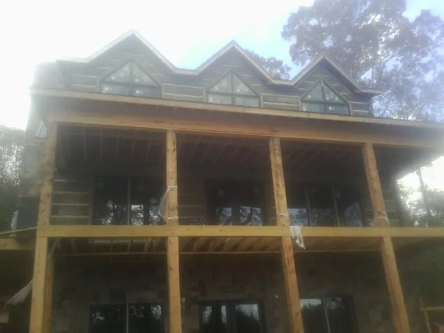 Dormers and porch framing on a large log home under construction — Roof Coating work by our crew in West Eaton