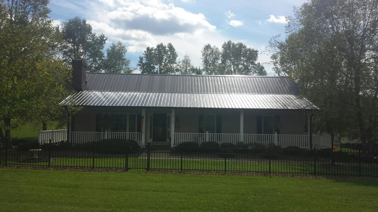 Gray metal roof on a brick ranch with a full width front porch — Gutter Guard Installation work by our crew in West Eaton