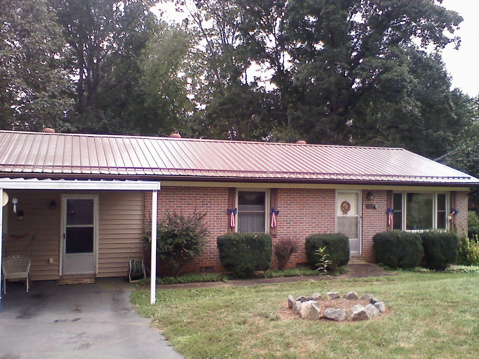 Bronze metal roof and carport on a brick ranch home — Roof Repair work by our crew in West Eaton