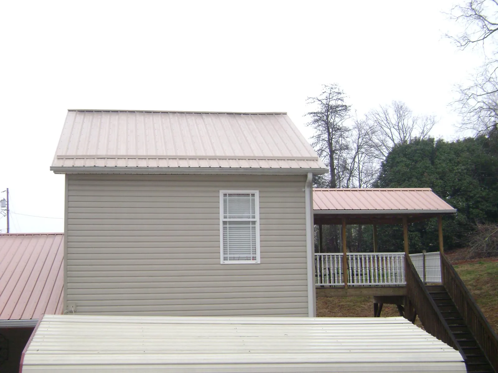 Tan metal roofs on a two story addition and attached porch, from a Roof Replacement job in West Eaton