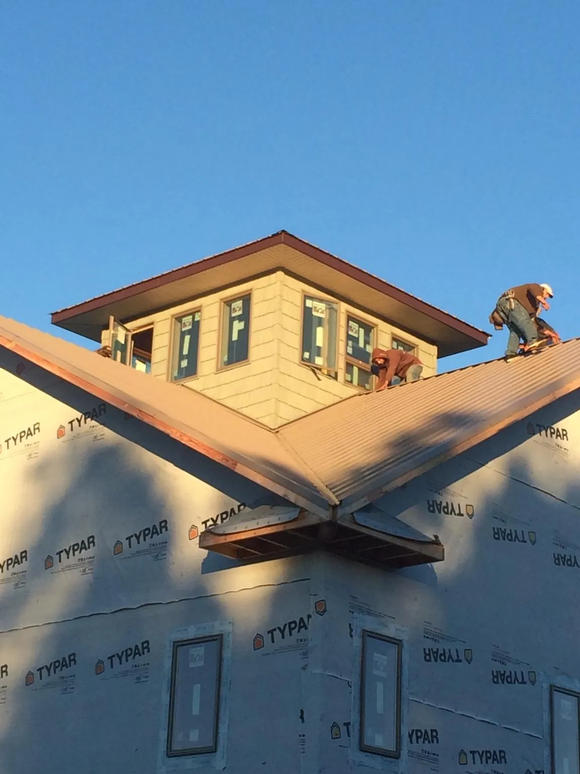 Roofers working around a rooftop cupola on a new metal roof at sunset — Roof Waterproofing in West Eaton by Roofing Brothers